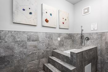 Three paintings of dogs are on the wall above a bathroom sink.