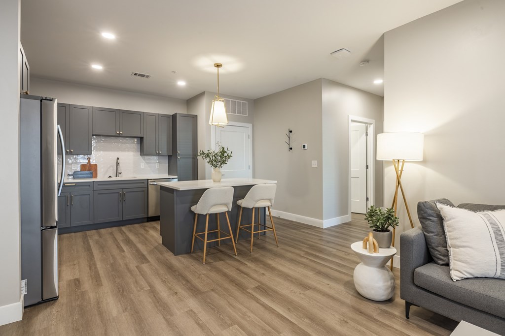 A modern kitchen with a refrigerator, bar stools, and a dining area.at Preserve at Sycamore Creek, Osage Beach, MO 65065