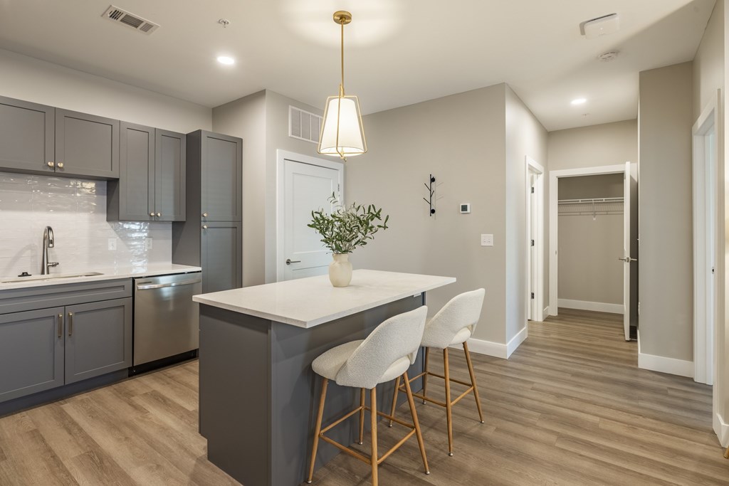 A modern kitchen with a white island and grey cabinets.at Preserve at Sycamore Creek, Missouri 65065