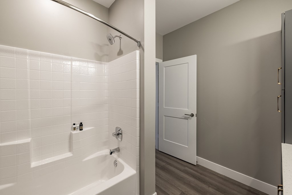 A white tiled bathroom with a white bathtub and a white door.at Preserve at Sycamore Creek, Osage Beach, MO 65065