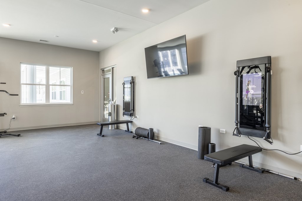 A spacious room with a bench, television, and exercise equipment.at Preserve at Sycamore Creek, Missouri 65065