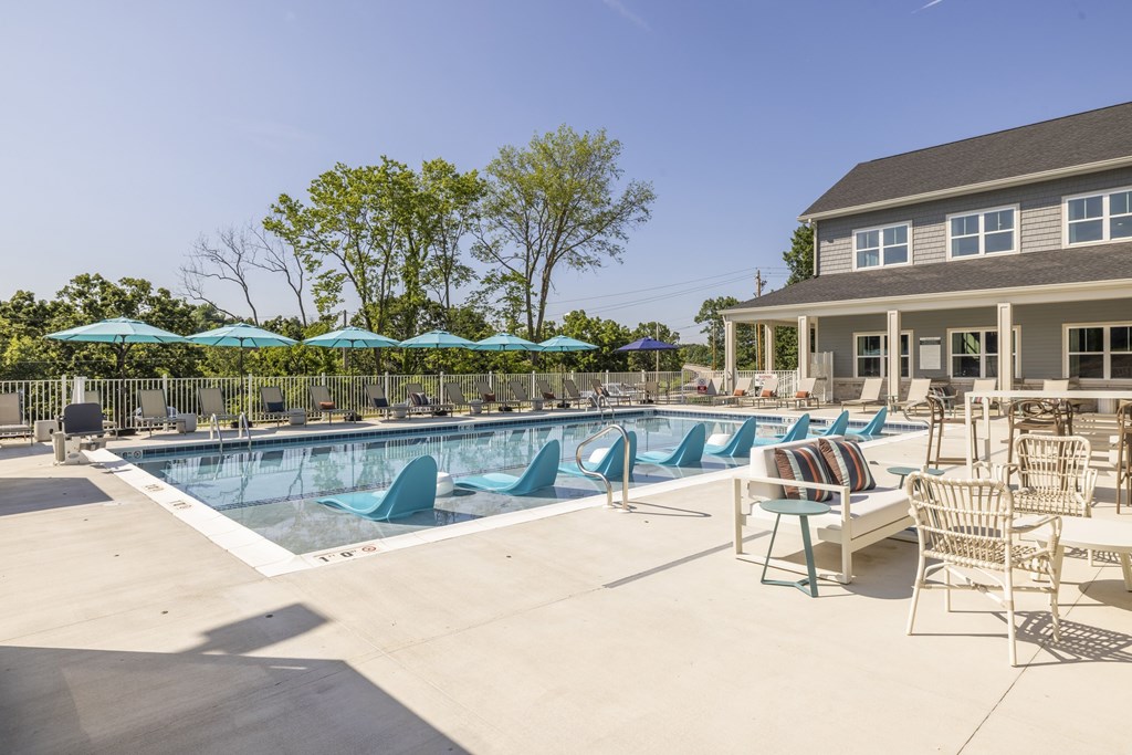 A pool with blue loungers and a building in the background.at Preserve at Sycamore Creek, Osage Beach, MO