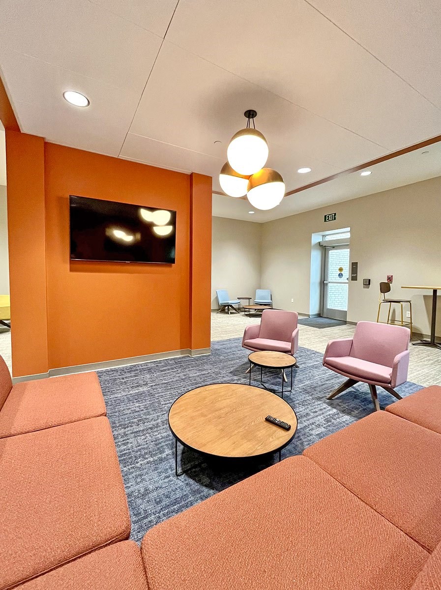 clubroom/resident lounge with sofa, two arm chairs, coffee table and television  at The Residences at Delmar DivINe, St Louis, MO
