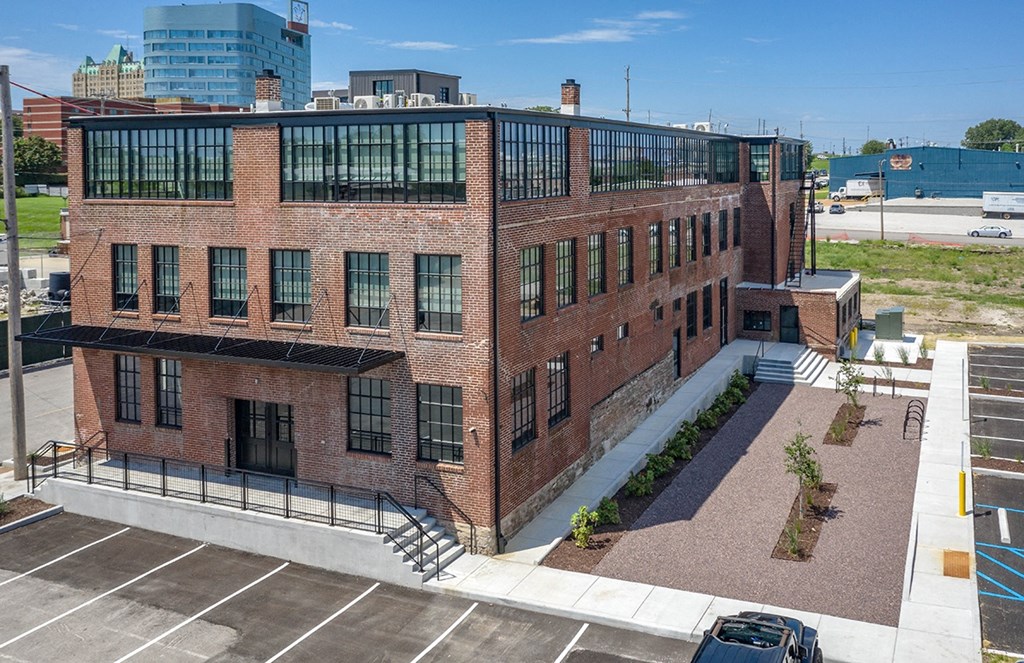 the exterior of a brick building with a balcony and a parking lot