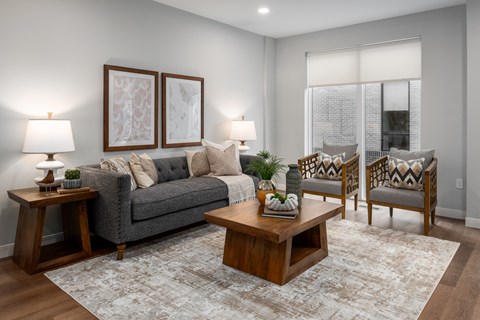 A living room with a grey couch, two chairs, a coffee table, and two lamps.