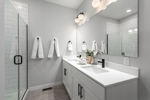 a white bathroom with a sink and a shower at The Flats & Terraces at Wildhorse Village, Missouri