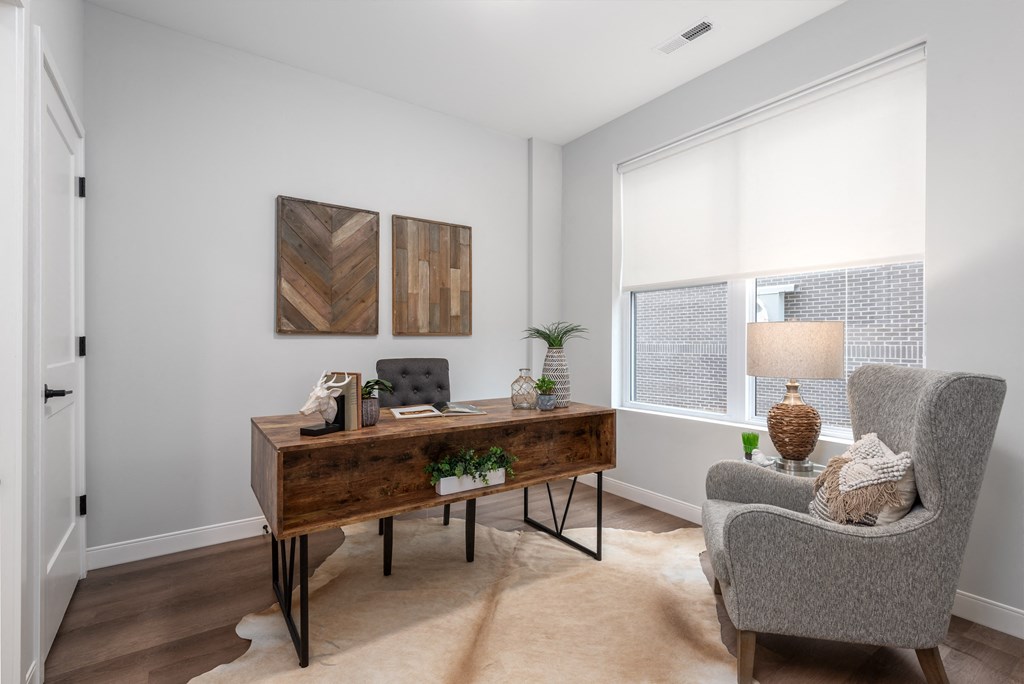 3rd bedroom/home office with rick plank flooring, oversized windows with custom shades, desk and arm chair at The Flats & Terraces at Wildhorse Village, Chesterfield, 63005