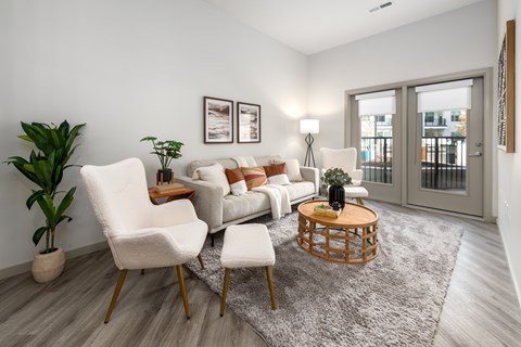 A living room with a grey rug, a white sofa, a white chair and a wooden coffee table.