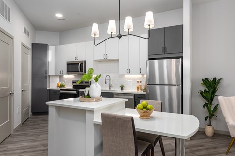 A modern kitchen with a dining table set for two.