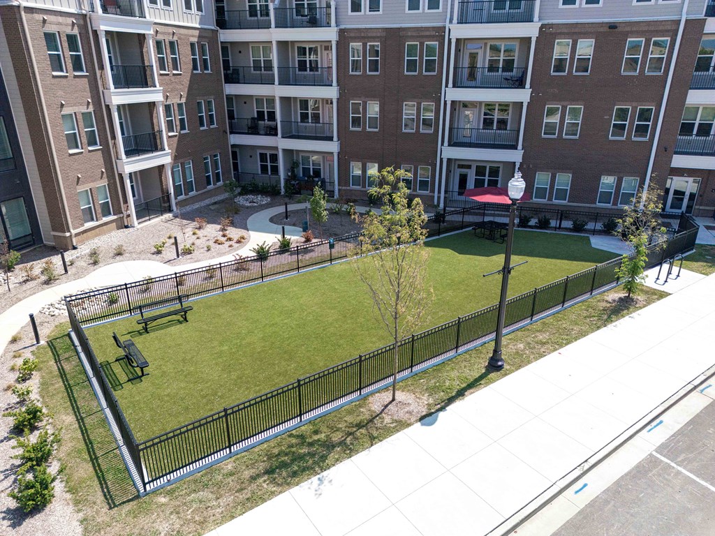A large apartment complex with a fenced in green space.
