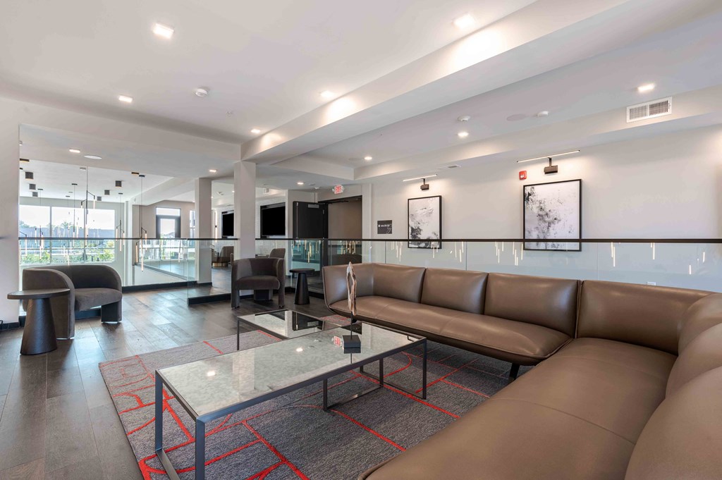 A modern waiting room with brown leather couches and a glass table.