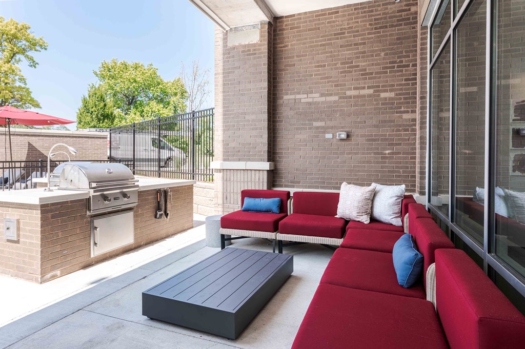 A red couch with blue cushions is on a patio.