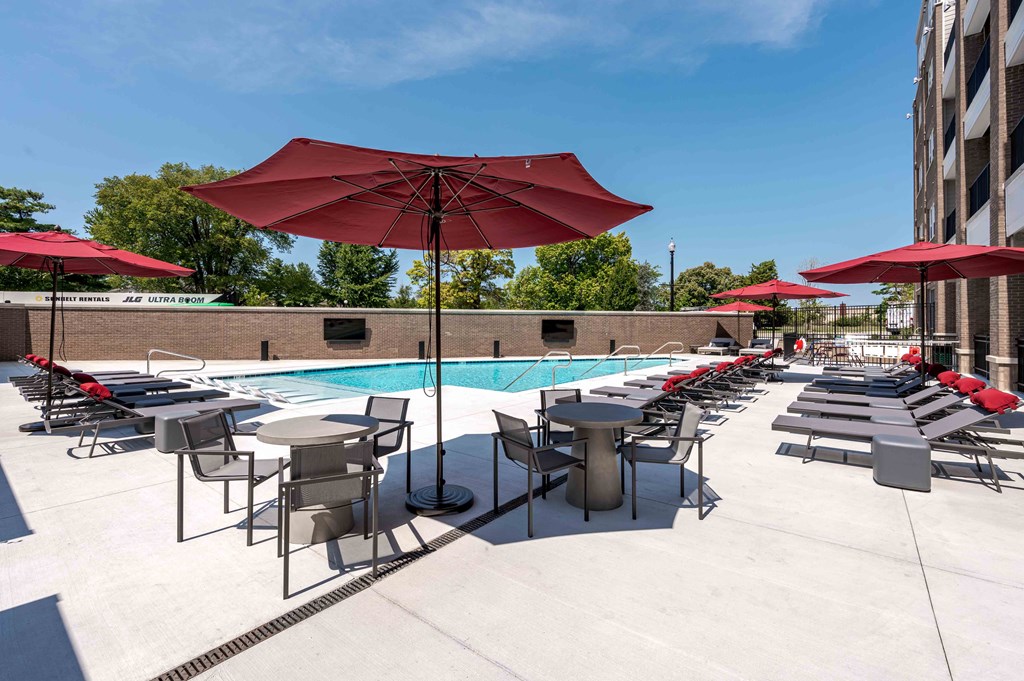 A pool area with red umbrellas and chairs.
