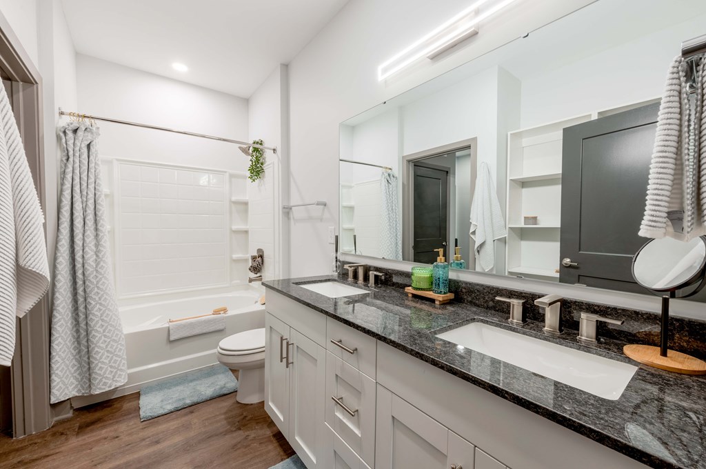 A bathroom with a black granite countertop and a white toilet.