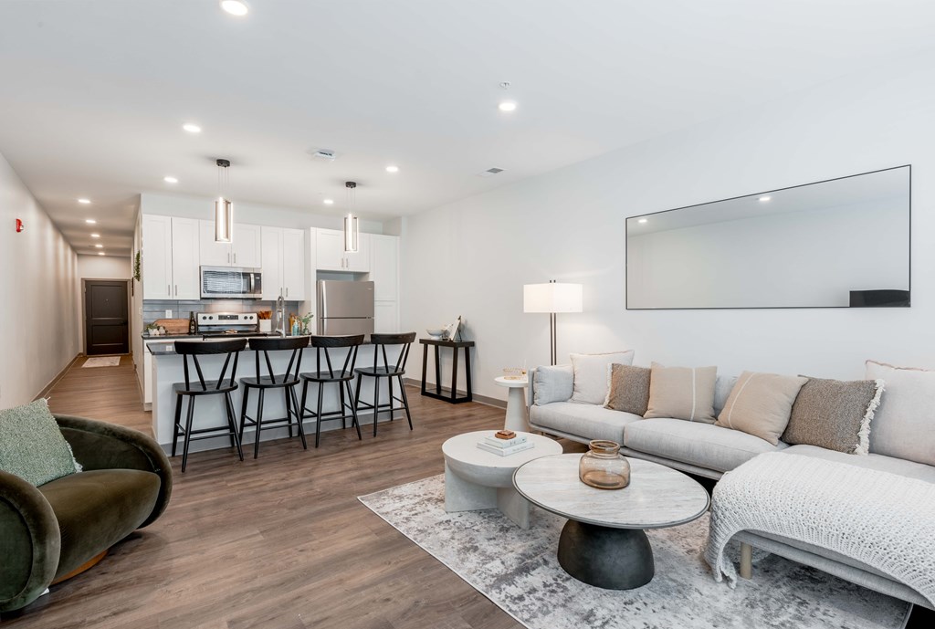 A modern living room with a kitchen area in the background.