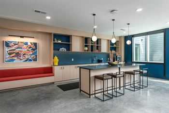 a kitchen with an island and stools in front of a table and a coucha kitchen with an island and stools in front of a table and a couch at The Edwin on Grand Apartments, St Louis, 63103