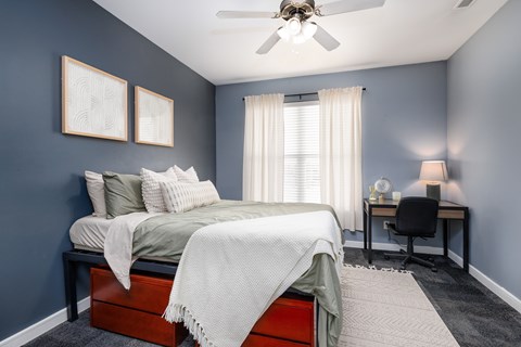 Bedroom with blue walls and desk area at The Landing Apartments, Missouri