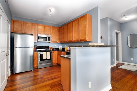 A kitchen with wooden cabinets and a stainless steel refrigerator.