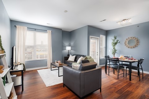 A living room with a grey sofa and a dining table set for six.