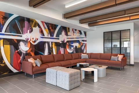 A living room with a large painting on the wall and a brown sofa.