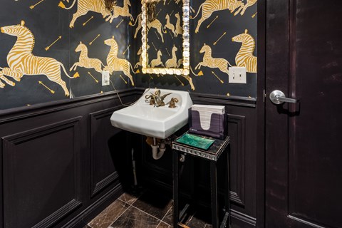 A bathroom with a black and gold theme featuring zebra wallpaper.
