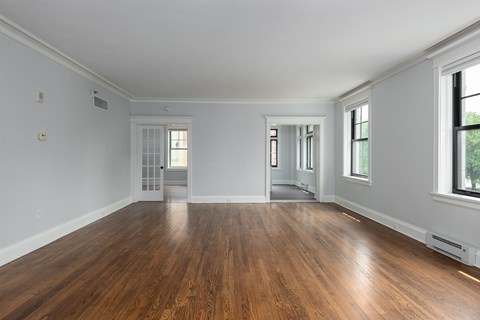 York House large living room with oak hardwood flooring, crown molding and french doors.
