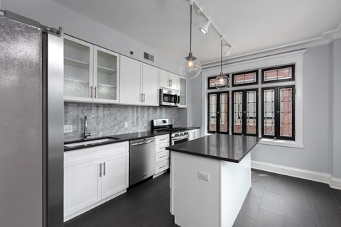 York House designer kitchen with gas stove, quartz countertops, stainless steel appliances, marble kitchen backsplash, and slate tile floor. Oversized windows, large kitchen island and soft close cabinetry.