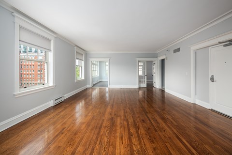 York House large living room with oak hardwood flooring, crown molding and french doors.