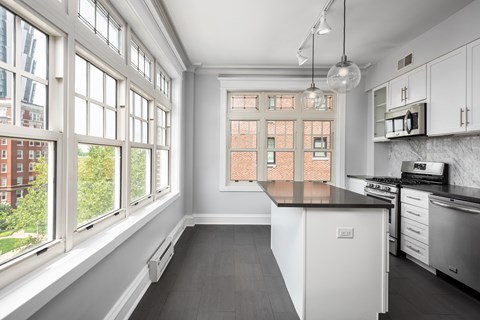 York House designer kitchen with gas stove, quartz countertops, stainless steel appliances, marble kitchen backsplash, and slate tile floor. Oversized windows, large kitchen island and soft close cabinetry.