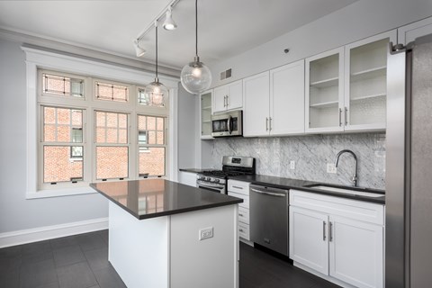 York House designer kitchen with gas stove, quartz countertops, stainless steel appliances, marble kitchen backsplash, and slate tile floor. Oversized windows, large kitchen island and soft close cabinetry.