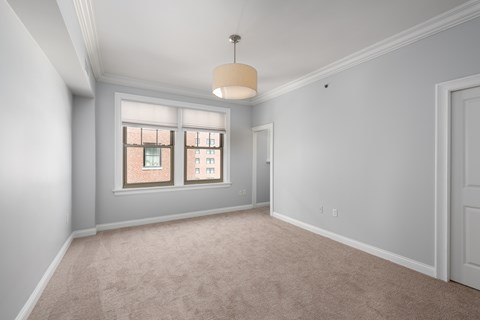 A room with a carpeted floor and a window with two panes of glass.