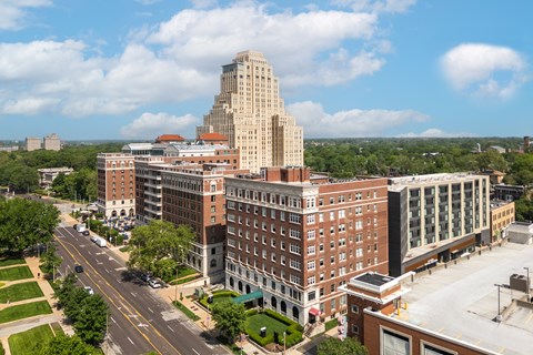 A tall building with a flat top is in the middle of a city.