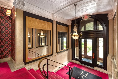 A hallway with a red carpet and a black door.