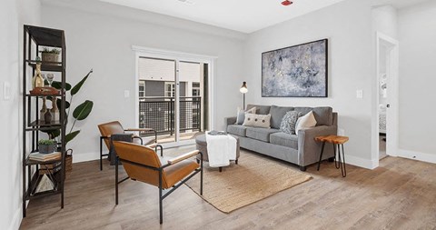 A living room with a grey couch, a brown chair, and a brown rug at The Oliver Apartments, Olivette, Missouri