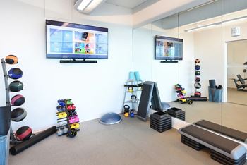 a fitness room with weights and a tv on the wall at Two Twelve Clayton, Clayton, MO