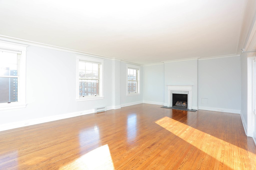 2 Bedroom living room with light wood flooring, white walls, 2 windows and fireplace at York House, Saint Louis, MO