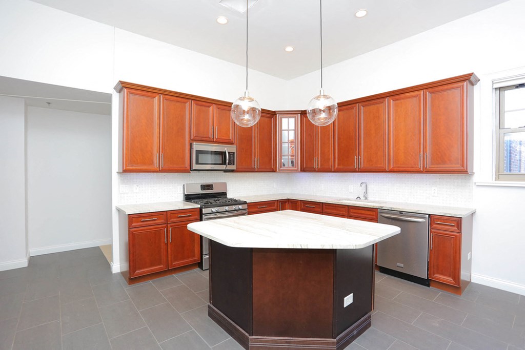 York House penthouse kitchen with maple cabinets, stainless steel appliances, granite countertops, pendant lighting and large island at York House, Saint Louis