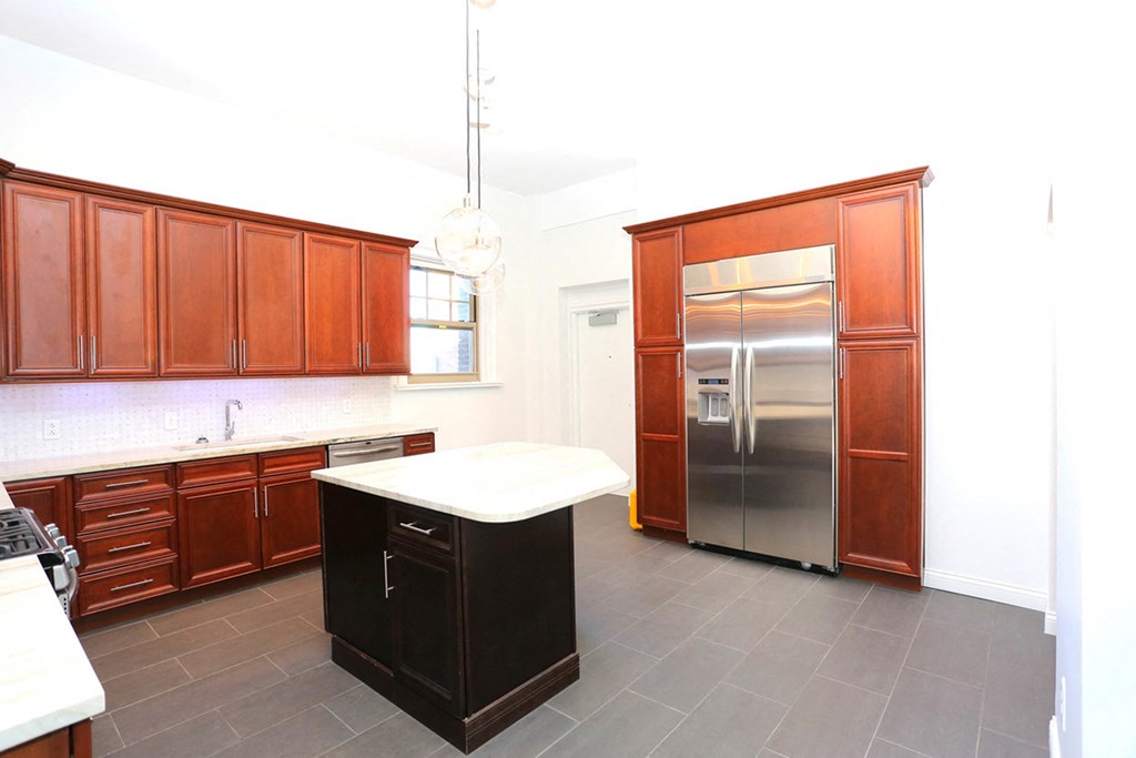 Penthouse kitchen with cherry cabinets, island with white top and stainless steel refrigerator at York House, Saint Louis, MO, 63108