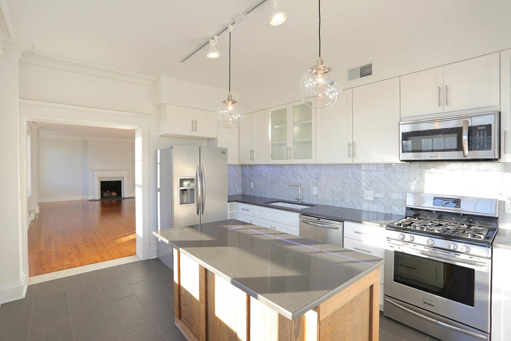 Kitchen with slate tile flooring, white cabinets, island and pendant lights at York House, Missouri, 63108