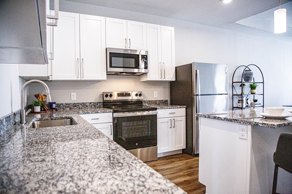 A modern kitchen with granite countertops and stainless steel appliances.