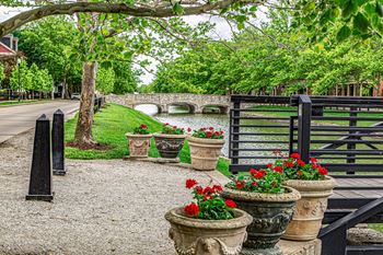 A bridge over a small river with a black gate and a row of flower pots.