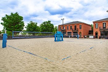 A sandy volleyball court with blue lines and a blue net.