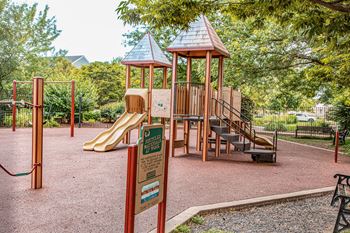 A playground with a yellow slide and a brown wooden structure.