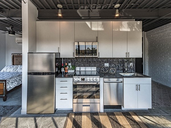 Steelcote Crossing kitchen with white cabinetry, black quartz countertops, stainless steel appliances, black tile backsplash and concrete floors at Steelcote Square, Missouri, 63103