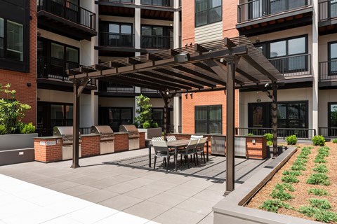 Resident courtyard with grilling stations, outdoor refrigerators, pergola and seating  at Chapter at the Streets of St Charles, Saint Charles, MO