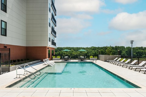 Sparkling swimming pool with sun tanning ledge, lounge chairs and two covered bistro tables  at Chapter at the Streets of St Charles, Missouri, 63303