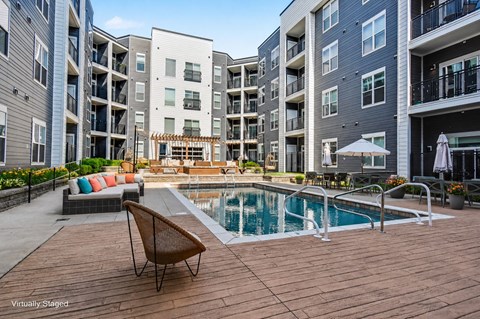 A chair is on a wooden deck next to a pool.