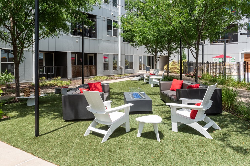 an outdoor lounge area with chairs and couches in front of a building at Grand Flats, St. Louis