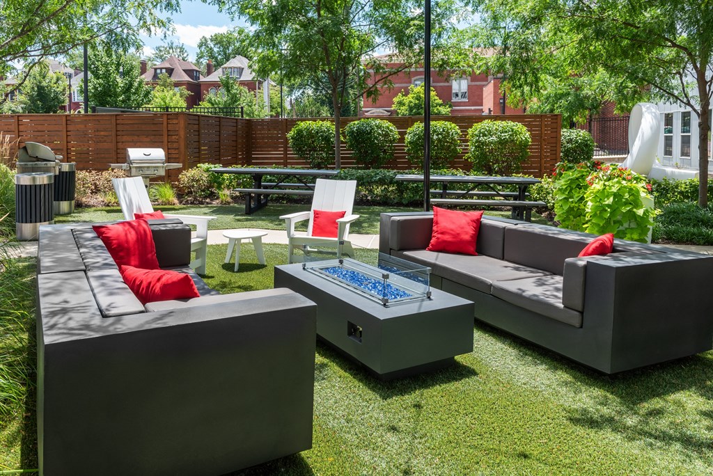 a backyard patio with couches and chairs and a fire pit at Grand Flats, St. Louis, MO