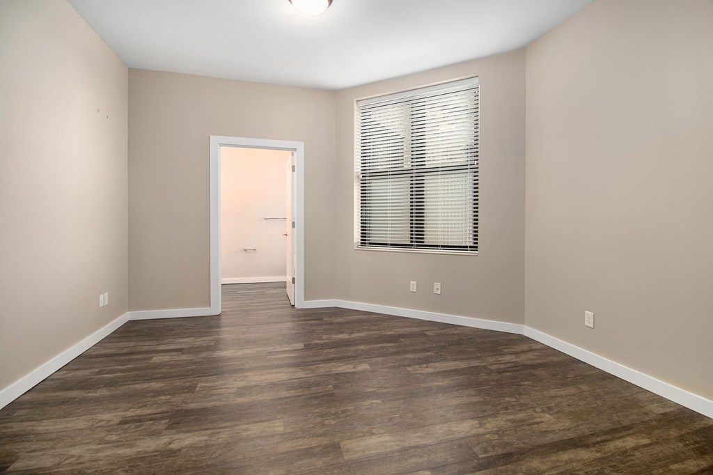 A room with wooden flooring and a window with blinds.